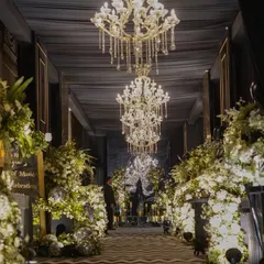 For a modern Sangeet, we designed this dramatic black luxe entrance. The combination of deep, dark drapes, grand chandeliers, and abundant white florals creates a sophisticated and moody atmosphere, promising a night of glamour and high energy.