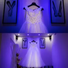 A creative shot of the bride's beautiful white wedding gown, elegantly displayed before the ceremony. The lighting and composition build anticipation for her entrance.