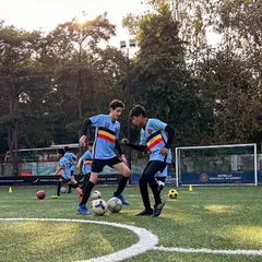 Two young players engage in a one on one drill, learning to use their body to shield the ball and their skills to beat a defender.