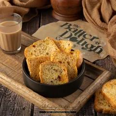 This shot of tea rusks is styled to evoke a sense of nostalgia and comfort. The wooden tray and a classic glass of chai create a perfect teatime scene.