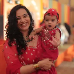 A happy photo of me and Gauri in matching red outfits for a "Mayra" ceremony. This shows how we dress up for family functions, creating opportunities for ethnic wear and kids' fashion brands to be featured.