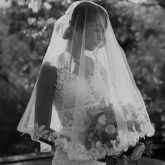 A timeless black and white portrait of a bride in her veil, holding her bouquet. The soft, natural light and her serene expression give this image an ethereal and classic beauty.