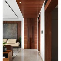 The main corridor features a continuous wooden ceiling and paneling that conceals a traditional temple. This allows for a seamless transition between the contemporary living spaces and the sacred puja area.