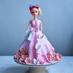 A classic Barbie doll cake, where the doll's skirt is made entirely of cake and covered in fondant. I teach how to structure the cake, create the layered dress effect, and add delicate fondant flowers and butterflies.