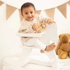 A classic first birthday portrait with a rocking horse and teddy bear. These timeless props create a nostalgic and sweet setting for milestone photos.