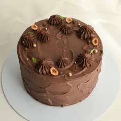 My Hazelnut Praline cake is a crowd favorite. It's a rich chocolate cake decorated with piped ganache, toasted hazelnuts, and crunchy praline pieces.