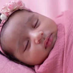A close-up of a peacefully sleeping newborn, wrapped snugly in pink. I focus on capturing the delicate features and serene expressions that make this stage so precious. The soft headband adds a perfect, gentle touch.