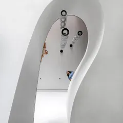 Looking down into the void of the sculptural staircase, the form appears like a ribbon of light. The design is not just about moving between floors, but about creating a powerful visual and spatial experience.