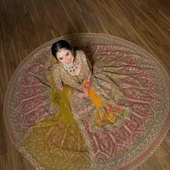 An aerial shot that captures the full circular flare of the bridal lehenga. The dupatta is draped to create a beautiful cascading effect.