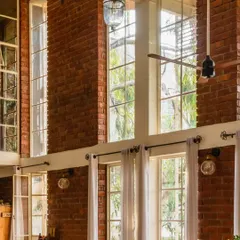 A closer look at the juxtaposition of delicate window frames against the robust, exposed brick wall. We love creating these moments of understated elegance in our designs.