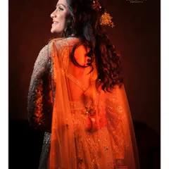 A beautiful back-profile shot of the bride, highlighted with warm, golden light. This portrait showcases the intricate details of her hairstyle and the elegant back of her gown.