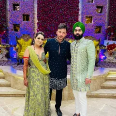A guest in our navy blue embroidered bandhgala poses with the happy couple. The groom's friend wears a contrasting mint green sherwani, also from our collection.