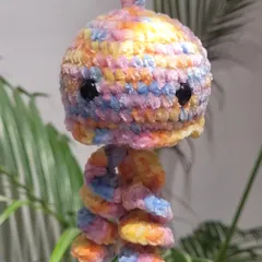 My first attempt at a baby jellyfish charm, made with rainbow pastel velvet yarn. It has cute little black eyes and curly tentacles. This piece is perfect as a hanging charm for a car mirror or in a kid's room.