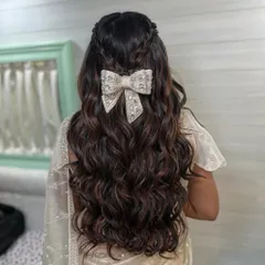 I love when brides want to add a playful and modern touch to their look. This half-up style with soft, flowing waves gets a chic update with a beautiful oversized bow accessory. It’s a perfect hairstyle for a Roka ceremony or an engagement party, blending romance with contemporary fashion.
