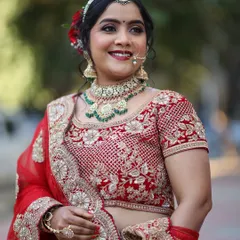 A happy and radiant bride in her red reception lehenga. The makeup is glamorous yet soft, with a focus on glowing skin and beautifully defined eyes.