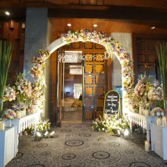 The entrance to Nikhil and Isha's Roka ceremony at the JW Marriott, featuring a grand floral arch in pastel shades and candlelit accents.