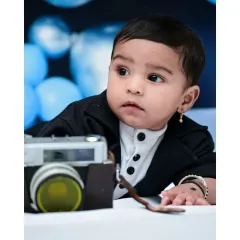 A close-up portrait from a six-month photoshoot, capturing this baby's thoughtful expression as he interacts with a vintage camera prop. These detailed shots focus on your baby's adorable features.
