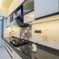 I design modular kitchens that are both beautiful and highly practical. This one features sleek handleless cabinets, a durable granite countertop, and a patterned tile backsplash that adds a unique touch, all lit perfectly for an efficient cooking experience.