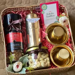 A sophisticated Rakhi hamper in a rose gold metal basket. This gift includes premium coffee, a coffee press, cashews, and traditional brass bowls.