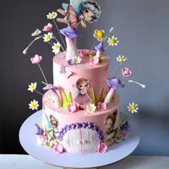 This two-tiered pink cake is a journey into a fairy-tale land. It is decorated with edible mushrooms, delicate sugar flowers, and printed fairy cutouts, with a larger fairy topper sitting on a mushroom.