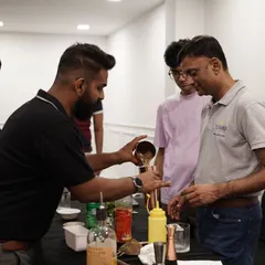 You get to be the bartender, and we're right there with you. Here, I'm guiding a participant through the steps of building a cocktail, ensuring everyone gets personal attention. Our beginner-friendly bartender class is perfect for anyone looking to learn a new skill.