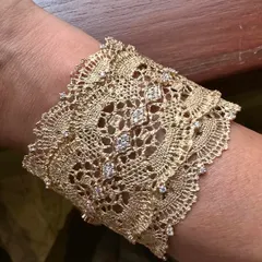 A close-up view of my signature lace cuff, worn on the wrist. This piece is inspired by delicate Chantilly lace and is meticulously hand-woven from 18k yellow gold, with natural diamonds scattered like dewdrops to catch the light.