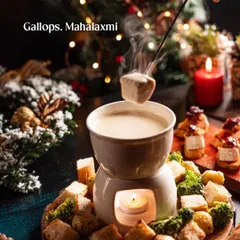A cozy shot of cheese fondue in a festive setting. The warm candlelight, Christmas decorations, and steaming fondue create a perfect image of a comforting holiday meal.