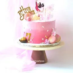 A cake for a young gymnast, celebrating her 7th birthday. This pink ombre cake is decorated with a gymnast topper, macarons, and delicate butterfly details.