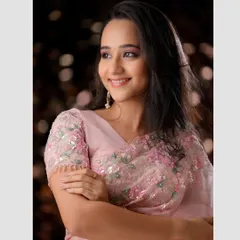 A classic three-quarter portrait that highlights the intricate floral embroidery on the saree blouse. The soft lighting and gentle smile create a timeless look.