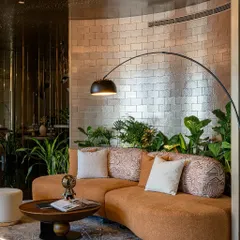 This is our vision for the modern workplace: The Midas Lounge, an office with no workstations. We used a curved sofa, metallic-finish brick tiles, and lush biophilic elements to design a space for connection and creativity, not just work.