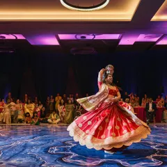 The bride and groom in the middle of their sangeet performance, captured in a beautiful lift. The custom-designed dance floor and dramatic lighting made their performance look even more spectacular.