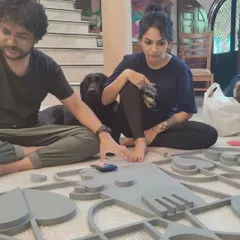 A candid moment in the studio with my teammate and my dog Kai, working on the floor with pieces of a new installation. This shows the collaborative and hands-on nature of our creative process.