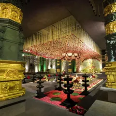 A perspective from between two of the massive, custom-fabricated pillars that defined the temple space. The pillars, finished to resemble ancient stone and gold, frame the view towards the main ceremony area, highlighting the architectural scale of the transformation.