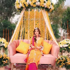 Here is a beautiful Mehendi or Haldi seating arrangement. I used a comfortable pink sofa set against a backdrop of hanging marigold strings and yellow drapes, creating the perfect spot for the bride to sit and for guests to take photos.