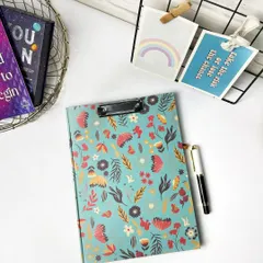 A clean, bright flatlay of a floral clipboard with a pen, styled with other desk accessories. This is a great shot for a product listing on an e-commerce site.