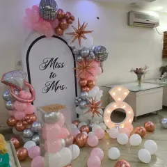 A beautiful 'Miss to Mrs.' setup for a bridal shower or bachelorette party. The pink, rose gold, and silver balloon arch, combined with a light-up diamond ring prop, is perfect for the bride-to-be.
