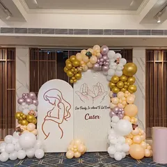 An elegant and modern baby shower backdrop. This setup features arched panels with custom line art, surrounded by a sophisticated balloon arrangement in pastel, white, and gold tones.