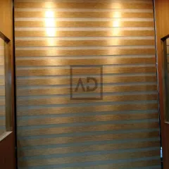 Here, the wooden zebra blinds are fully closed, providing privacy and a warm, textured wall effect. The backlighting highlights the clean, horizontal lines that are characteristic of this popular blind style.