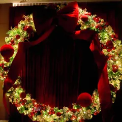 A giant, illuminated Christmas wreath creates a stunning photo backdrop, perfect for a festive party.