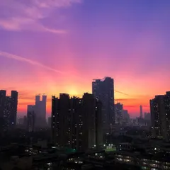 A perfect sunset captured on a phone, showing vibrant purple and orange hues filling the sky between Mumbai's buildings.