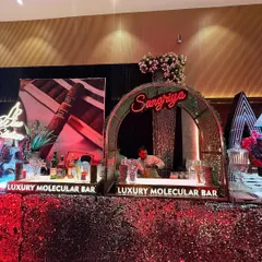 It's all in the details. This glamorous bar setup features a vibrant red sequin-paneled counter that catches the light beautifully, paired with a dedicated, neon-lit 'Sangriya' station to create an inviting and high-energy focal point.