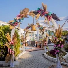 The entrance to a fun pre-wedding carnival, featuring a bohemian-style arch decorated with pampas grass and colorful flowers.