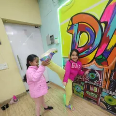 Stretching can be fun too. Our young dancers help each other with leg holds and kicks, building both flexibility and teamwork in the process.