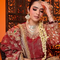 A close-up portrait of a model in a traditional red bridal ensemble, highlighting the detailed jewelry and elegant makeup.