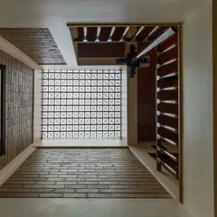 A large window with a delicate jaali pattern filters the harsh sun, casting soft, diffused light onto the brick-paved floor below. This is how we can get the daylight we need without the heat.