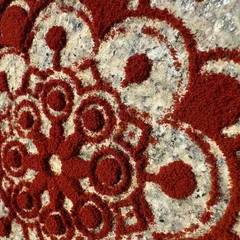 A close-up of a Rangoli pattern created with natural red powder. Rangoli is a traditional Indian art form used to bring good luck, and making the powders from natural sources makes it even more special.