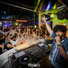 Connecting with the crowd is key to a great party. Here I am on the mic at Cafe Mambo, getting everyone's hands in the air for a massive moment. I know how to read the room and keep the energy at its peak all night long.