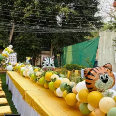 A closer look at the playful table runner for the kids' seating area. Large foil balloons shaped like a tiger and zebra pop out from the arrangement, adding a delightful touch to the safari birthday party decor.