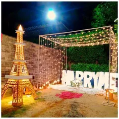 Another view of the romantic outdoor proposal scene, showcasing the glowing Eiffel Tower prop and the bed of rose petals.