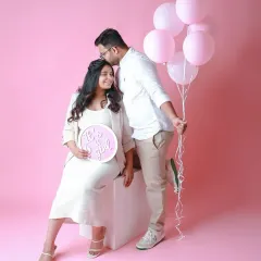 A sweet gender reveal for a baby girl. The pink balloons and "It's a girl" sign make for a beautiful and celebratory couple's portrait.